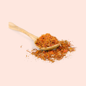 A small pile of red-orange sandalwood hydrosol with a wooden spoon, against a white background.