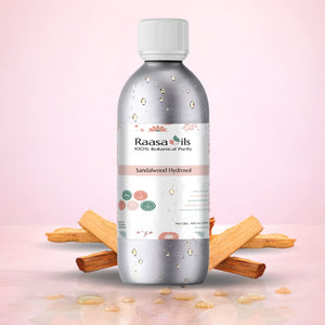 Raasa Oils Sandalwood Hydrosol bottle with sandalwood pieces on a light pink background