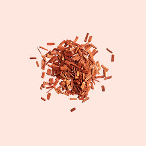 A pile of brown sandalwood chips against a beige background