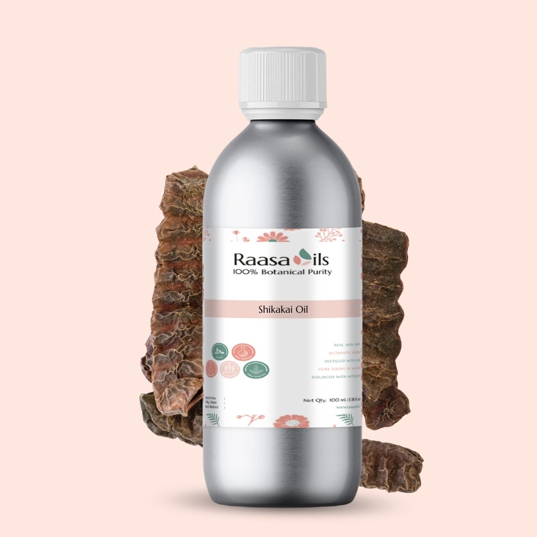 Bottle of Raasa Oils Shikakai Oil with a piece of soap root on a light pink background