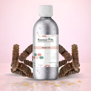 Bottle of Raasa Oils Shikakai Oil with dried shikakai roots on a pink background