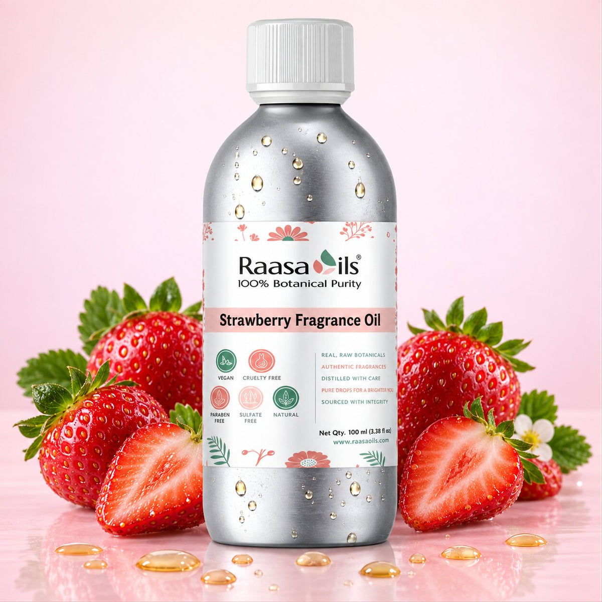 A bottle of Raasa Oils Strawberry Fragrance Oil centered on a pink background, surrounded by fresh strawberries and gold droplets. The bottle is metallic silver with a white cap and a white label featuring pink and green accents.
