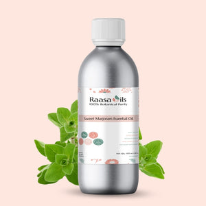 Silver bottle of Raasa Oils Sweet Marjoram Essential Oil with green leaves on a light pink background
