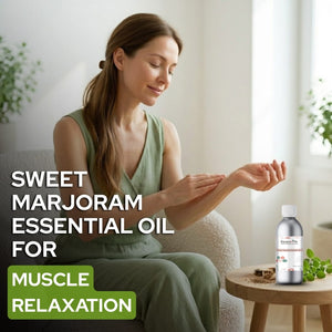 Woman applying sweet marjoram essential oil to her hand with a bottle of the product on a table.