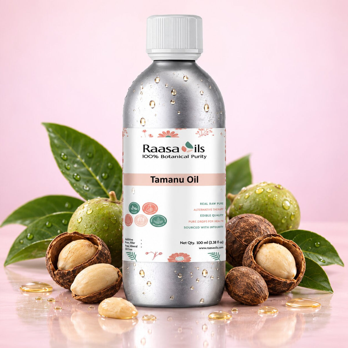 A bottle of Raasa Oils Tamanu Oil centered on a pink background, surrounded by green leaves, green nuts, and cracked nuts with visible oil droplets. The bottle is metallic silver with a white cap and a white label featuring the Raasa Oils brand and Tamanu Oil text.
