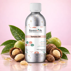 A bottle of Raasa Oils Tamanu Oil centered on a pink background, surrounded by green leaves, green nuts, and cracked nuts with visible oil droplets. The bottle is metallic silver with a white cap and a white label featuring the Raasa Oils brand and Tamanu Oil text.