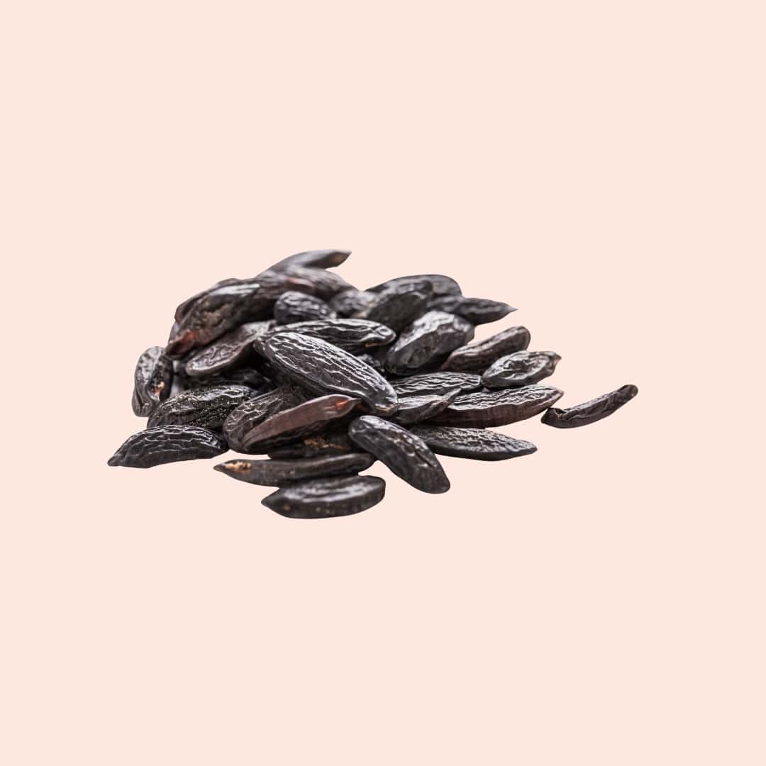 Pile of dark raisins on a light pink background