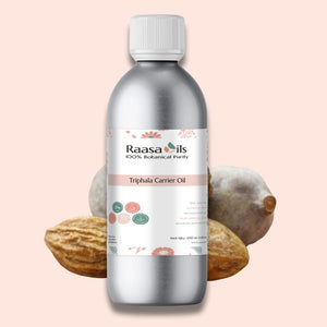Bottle of Raasa Oils Triphala Carrier Oil with Triphala fruits on a light pink background
