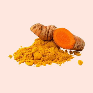 Turmeric root and powder on a light pink background