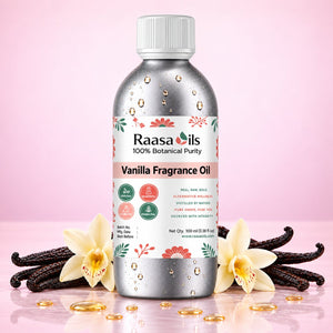 A bottle of Raasa Oils Vanilla Fragrance Oil centered on a pink background, surrounded by vanilla beans, cream orchids, and scattered gold droplets. The bottle is metallic silver with a white cap and a floral label.
