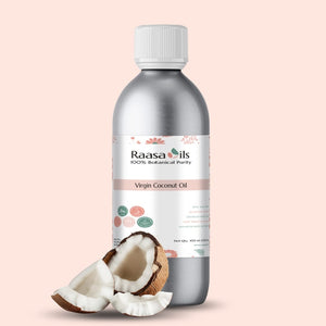 Bottle of Raasa Oils Virgin Coconut Oil with a half-coconut on a light pink background
