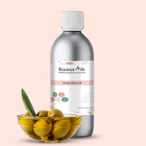 Bottle of Raasa Oils Virgin Olive Oil with a bowl of olives on a light pink background
