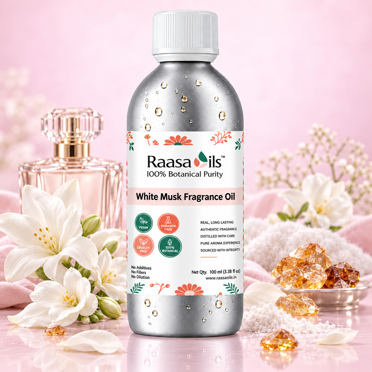 A bottle of Raasa oils White Musk Fragrance Oil stands centered on a reflective surface, surrounded by white flowers, crystals, and a perfume bottle against a soft pink background.