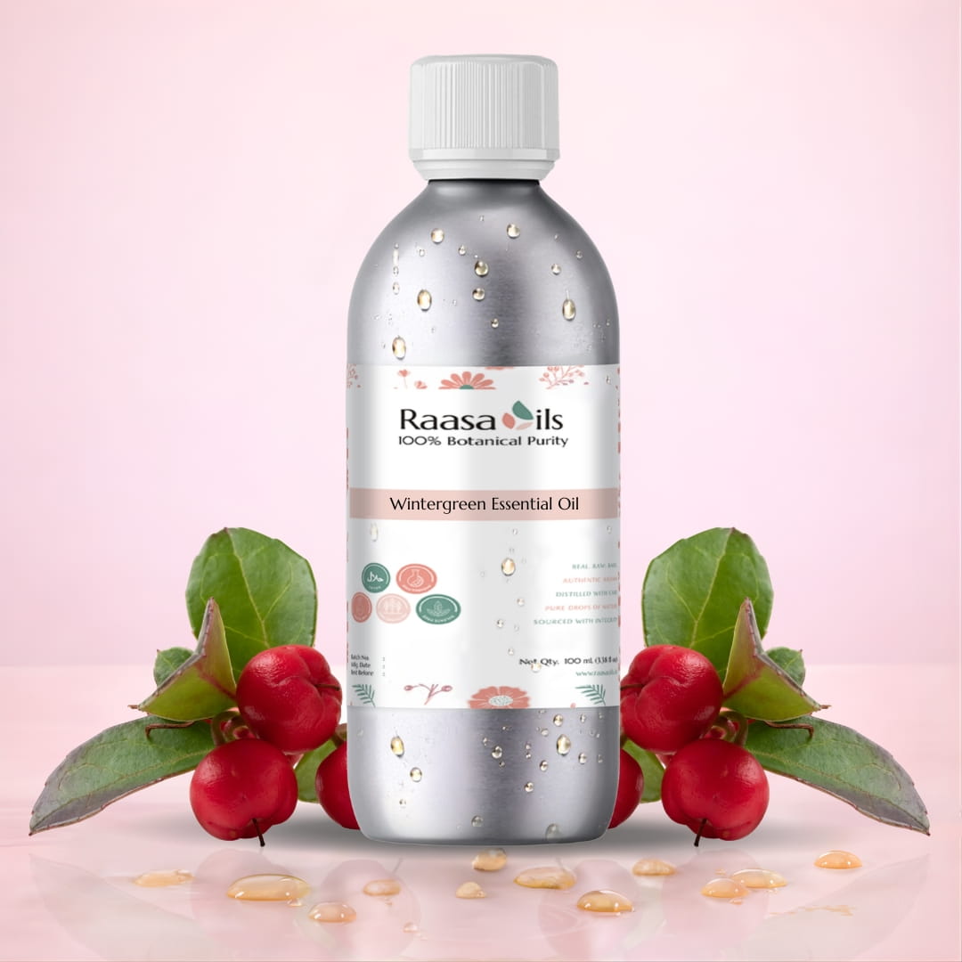 Raasa Oils Wintergreen Essential Oil bottle on a light pink background with wintergreen leaves and berries.