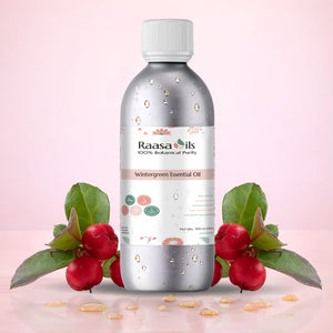 Raasa Oils Wintergreen Essential Oil bottle on a light pink background with wintergreen leaves and berries.