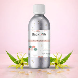 Bottle of Raasa Oils Ylang Ylang Hydrosol with yellow flowers on a light pink background