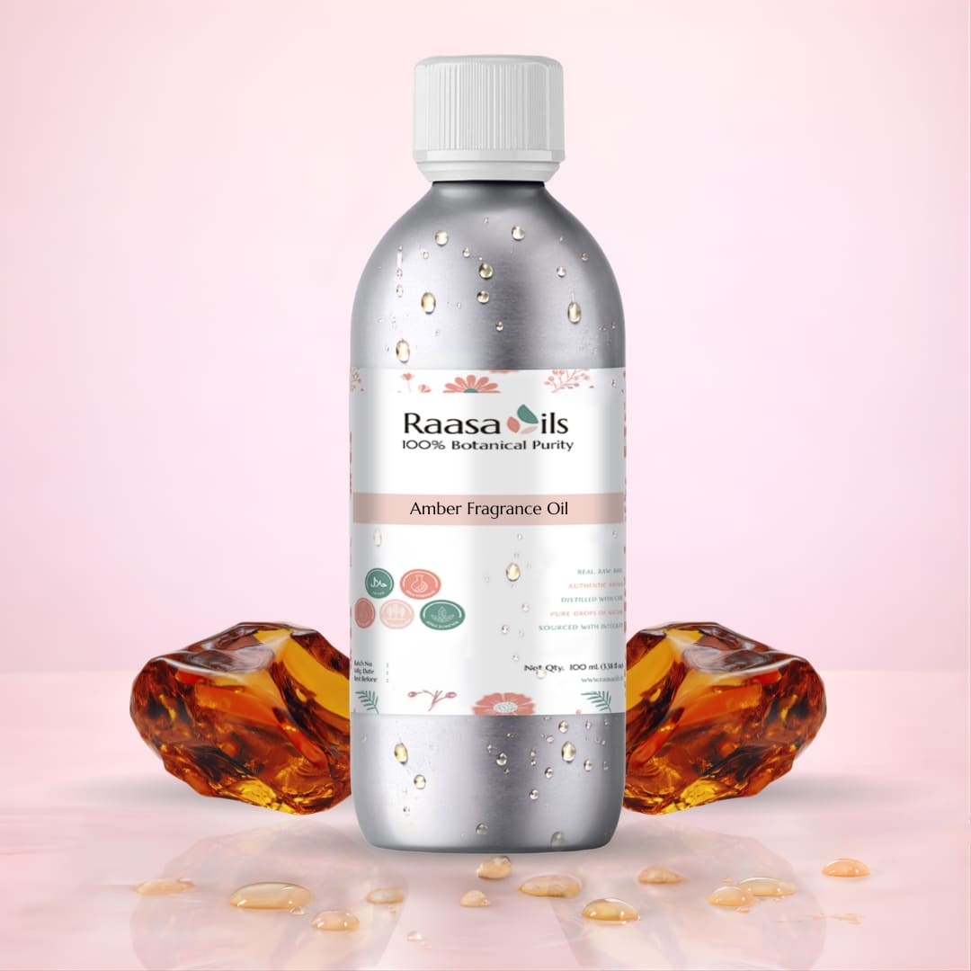 Bottle of Raasa Oils Amber Fragrance Oil with amber stones on a pink background