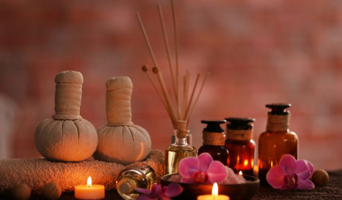 Aromatherapy setup with bottles, candles, and flowers on a blurred background
