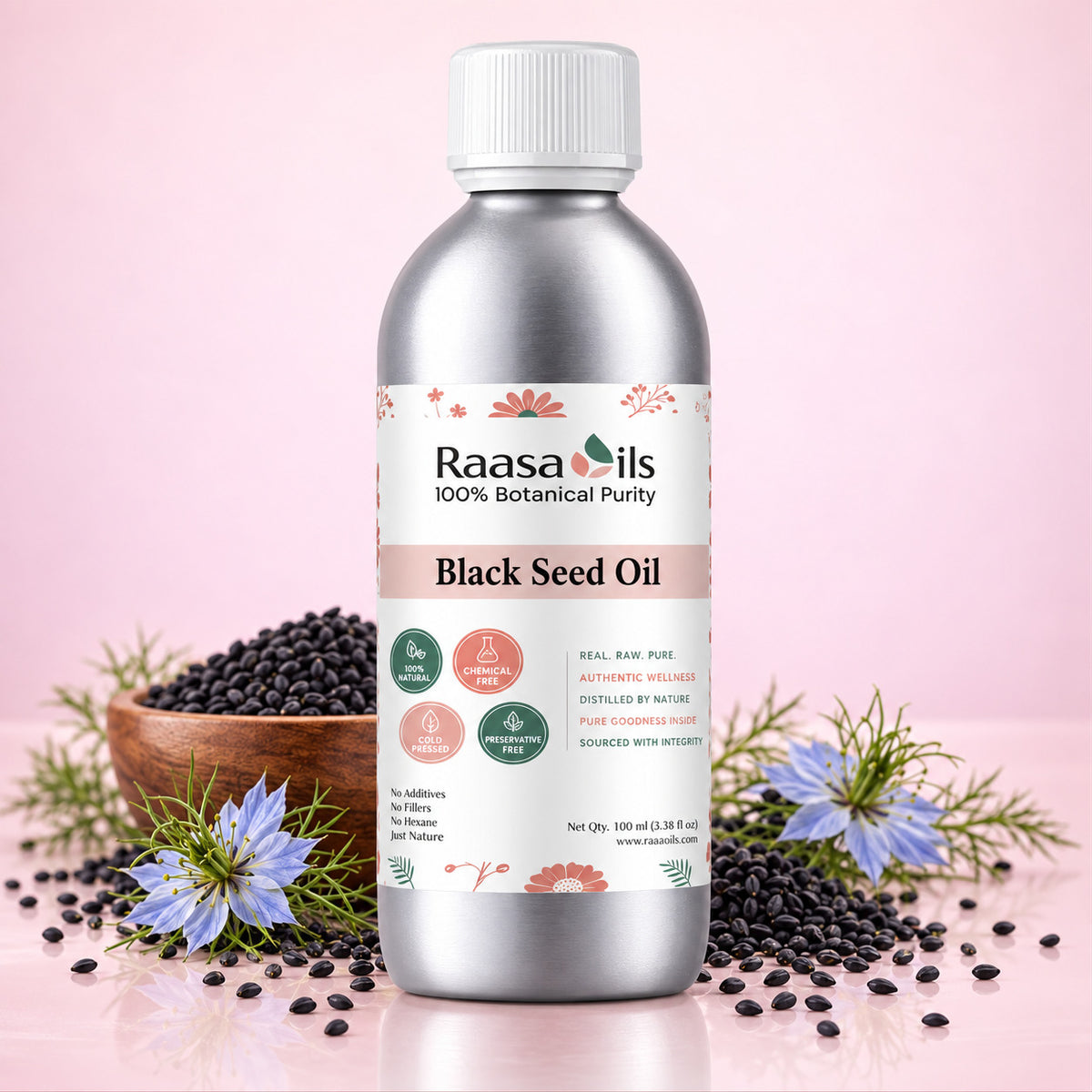 A bottle of Raasa Oils Black Seed Oil centered on a light pink background, surrounded by loose black seeds, a small wooden bowl, and blue flowers. The bottle is metallic silver with a white cap and a white label featuring the brand name Raasa Oils and the product name Black Seed Oil.