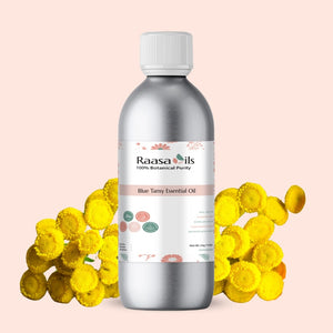 Silver bottle of Raasa Oils Blue Tansy Essential Oil with yellow flowers on a light pink background