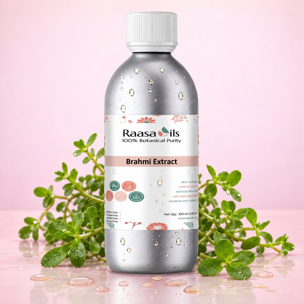 A bottle of Raasa Oils Brahmi Extract centered on a pink background, surrounded by green herbal sprigs and water droplets. The bottle is metallic silver with a white cap and a white label featuring pink and green accents.