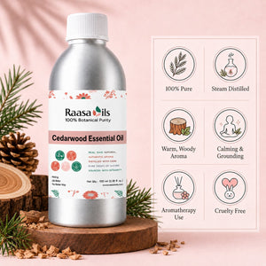 A bottle of Raasa oils Cedarwood Essential Oil displayed on a wooden slice pedestal with pine branches and wood chips, next to a graphic card detailing product benefits on a soft pink background.