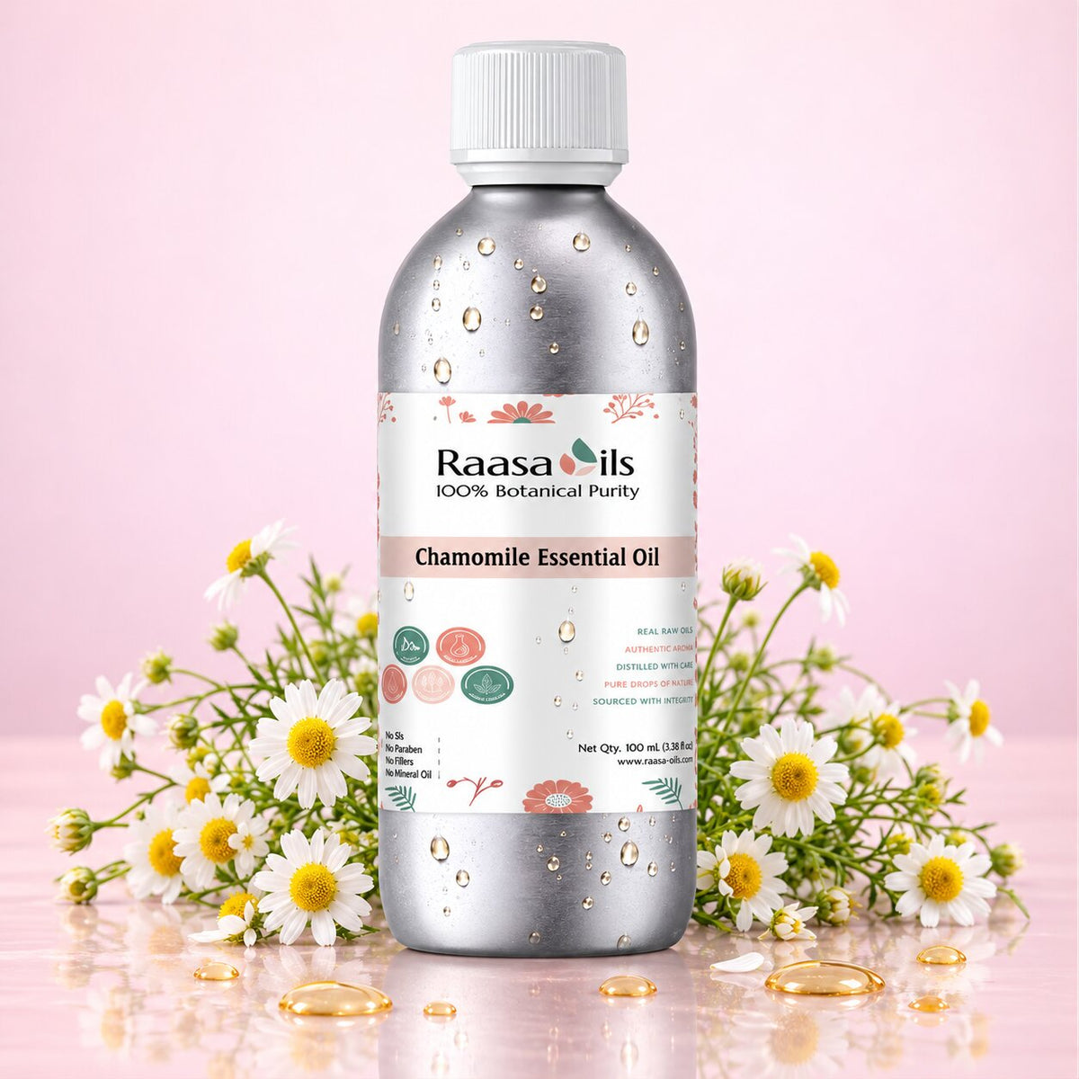 A bottle of Raasa oils Chamomile Essential Oil centered on a pink background, flanked by chamomile flowers and gold oil droplets. The bottle is metallic silver with a white cap and a white label featuring the brand name 'Raasa oils'.