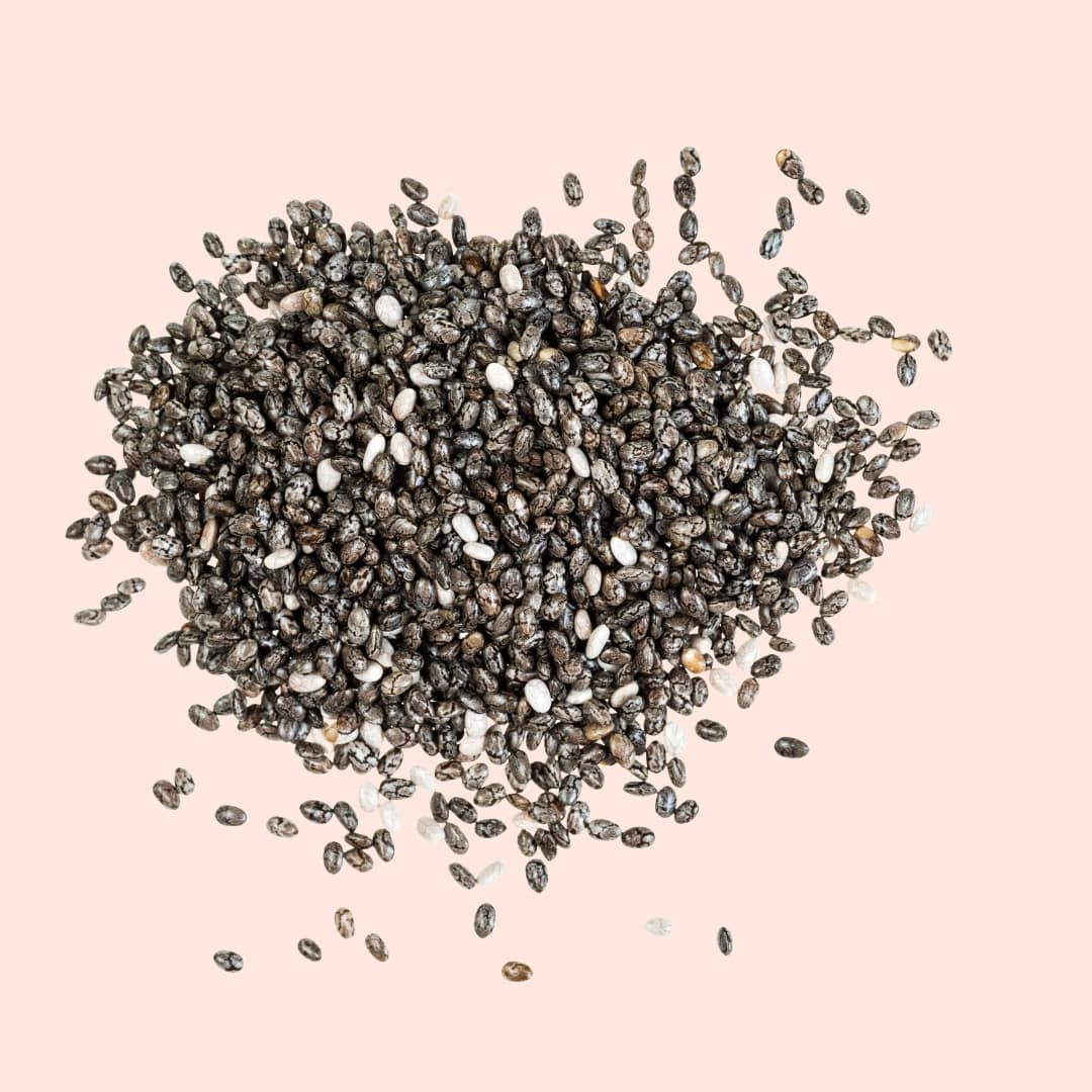 Pile of chia seeds on a pink background