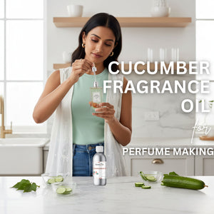 Woman holding a bottle of cucumber fragrance oil with cucumbers and leaves on a table.