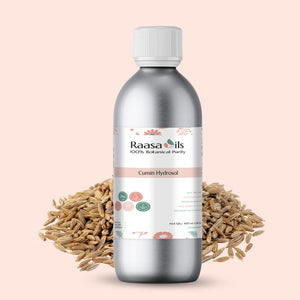 Bottle of Raasa Oils Cumin Hydrosol with cumin seeds on a light pink background