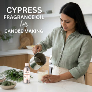 Woman pouring liquid into a glass with Cypress fragrance oil for candle making, in a kitchen setting.
