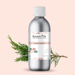 Bottle of Raasa Oils Cypress Hydrosol with a branch on a light pink background