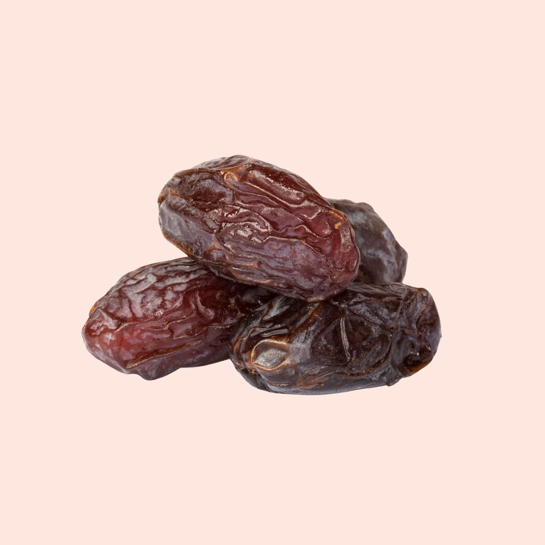 Three dried dates on a light pink background