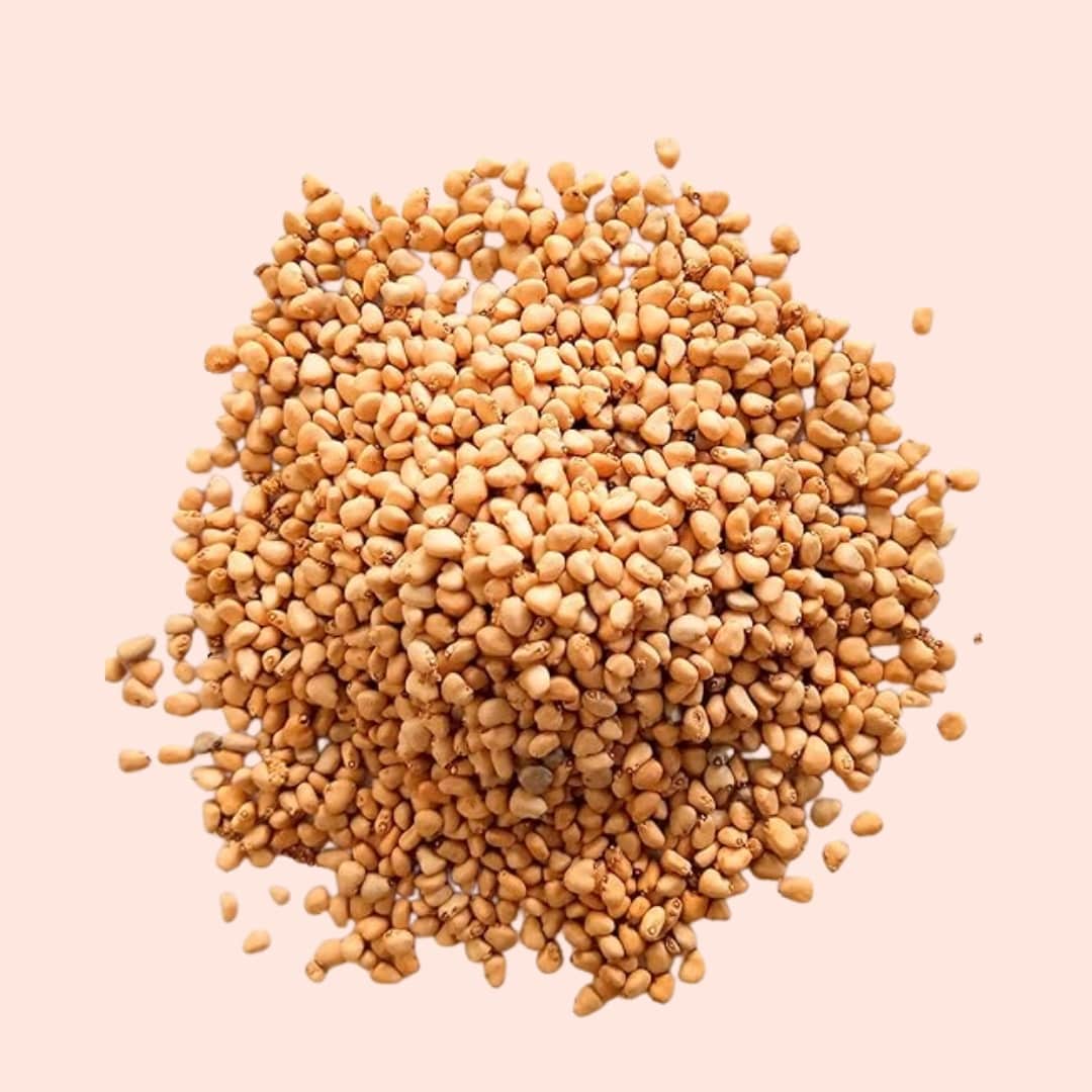Pile of fenugreek seeds on a light pink background