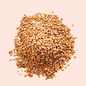 Pile of fenugreek seeds on a light pink background