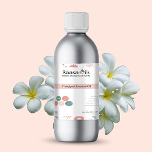 Raasa Oils Frangipani Essential Oil bottle with flowers on a light pink background