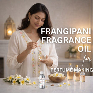 Woman holding a bottle of frangipani fragrance oil with flowers and bottles on a table.