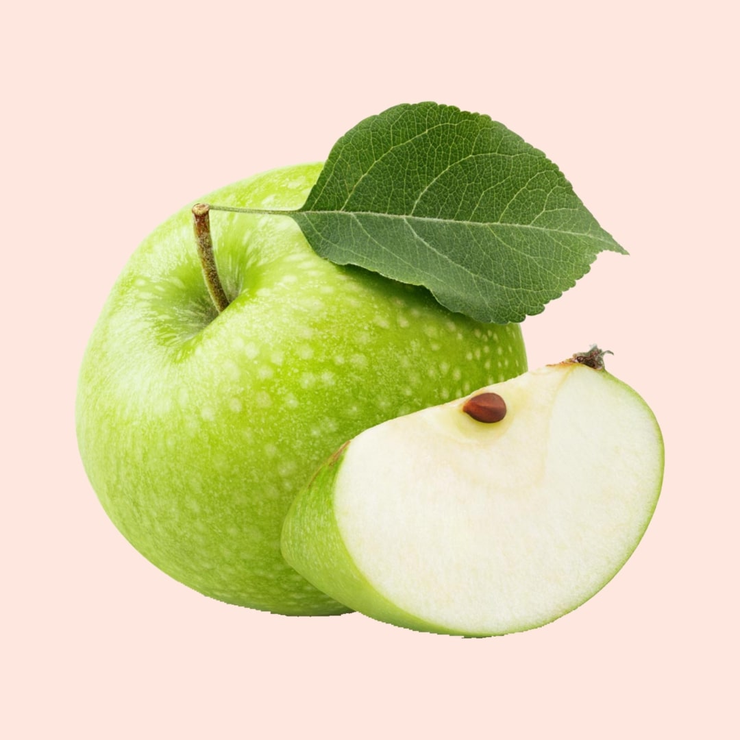 Green apple with a slice and a leaf on a light pink background