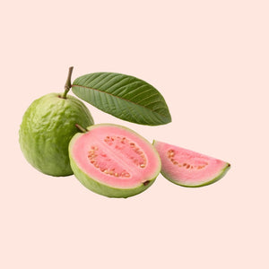 Guava fruit with a slice and leaves on a light pink background