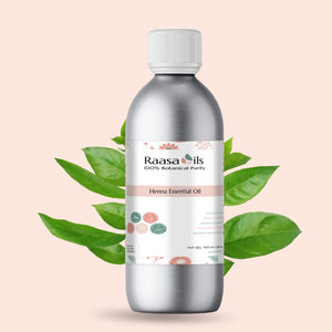 Bottle of Raasa Oils Henna Essential Oil with green leaves on a light pink background
