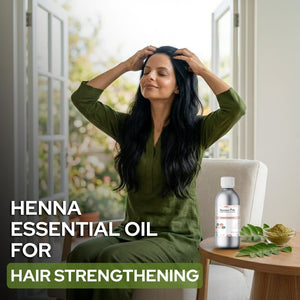 Woman with long dark hair sitting in a room with a bottle of henna essential oil on a table.