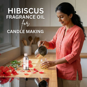 Woman pouring a liquid into a jar with hibiscus flowers and fragrance oil bottle on a table.