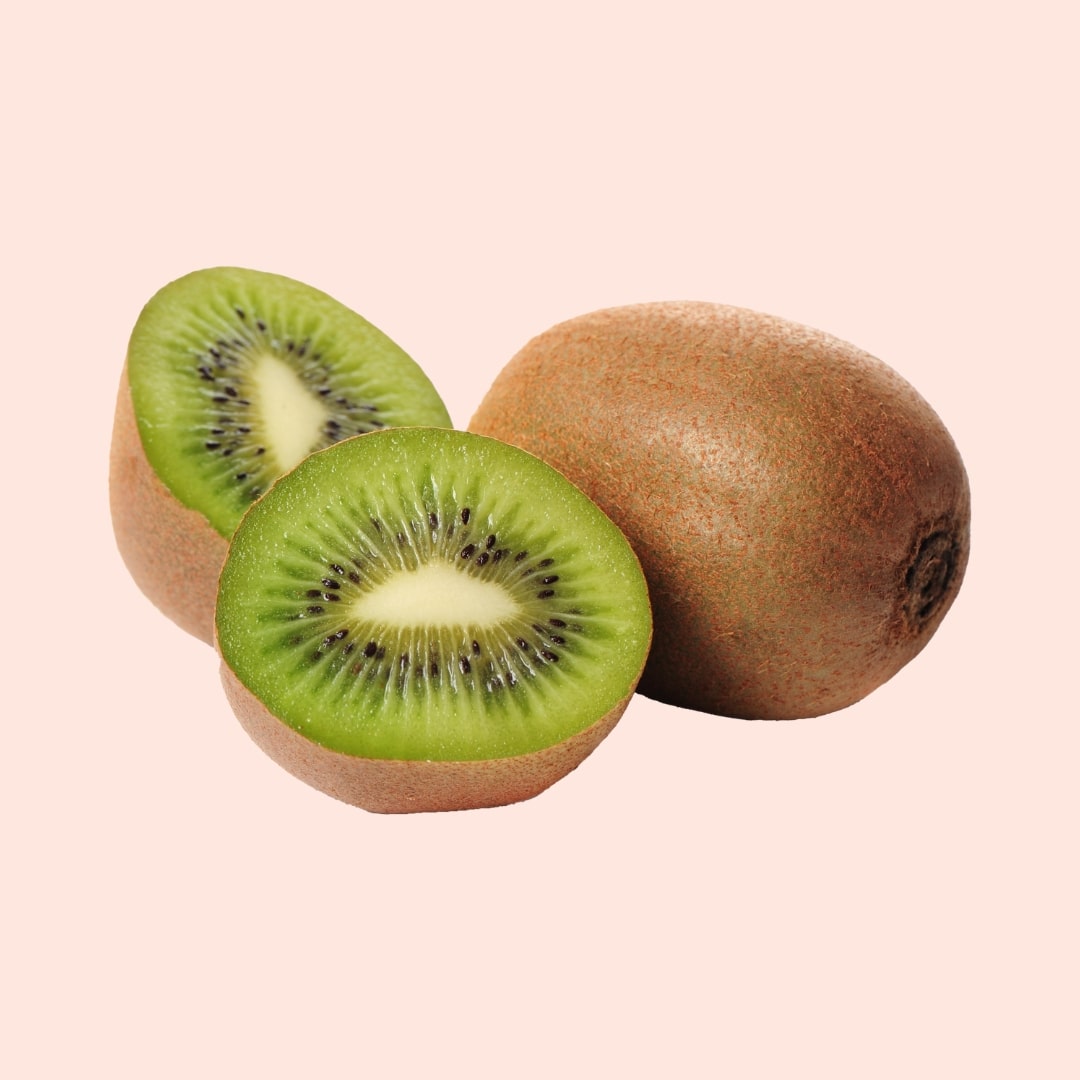 Two kiwis, one sliced open, on a light pink background