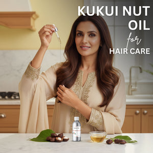 Woman with long brown hair holding kukui nut oil, with a bottle and leaves on a kitchen counter.