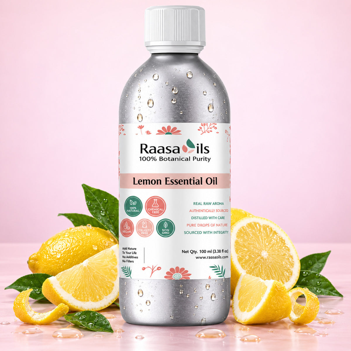 A bottle of Raasa Oils Lemon Essential Oil centered on a pink background, surrounded by fresh lemons, lemon slices, and green leaves. The bottle is metallic silver with a white cap and a white label featuring pink and green accents.