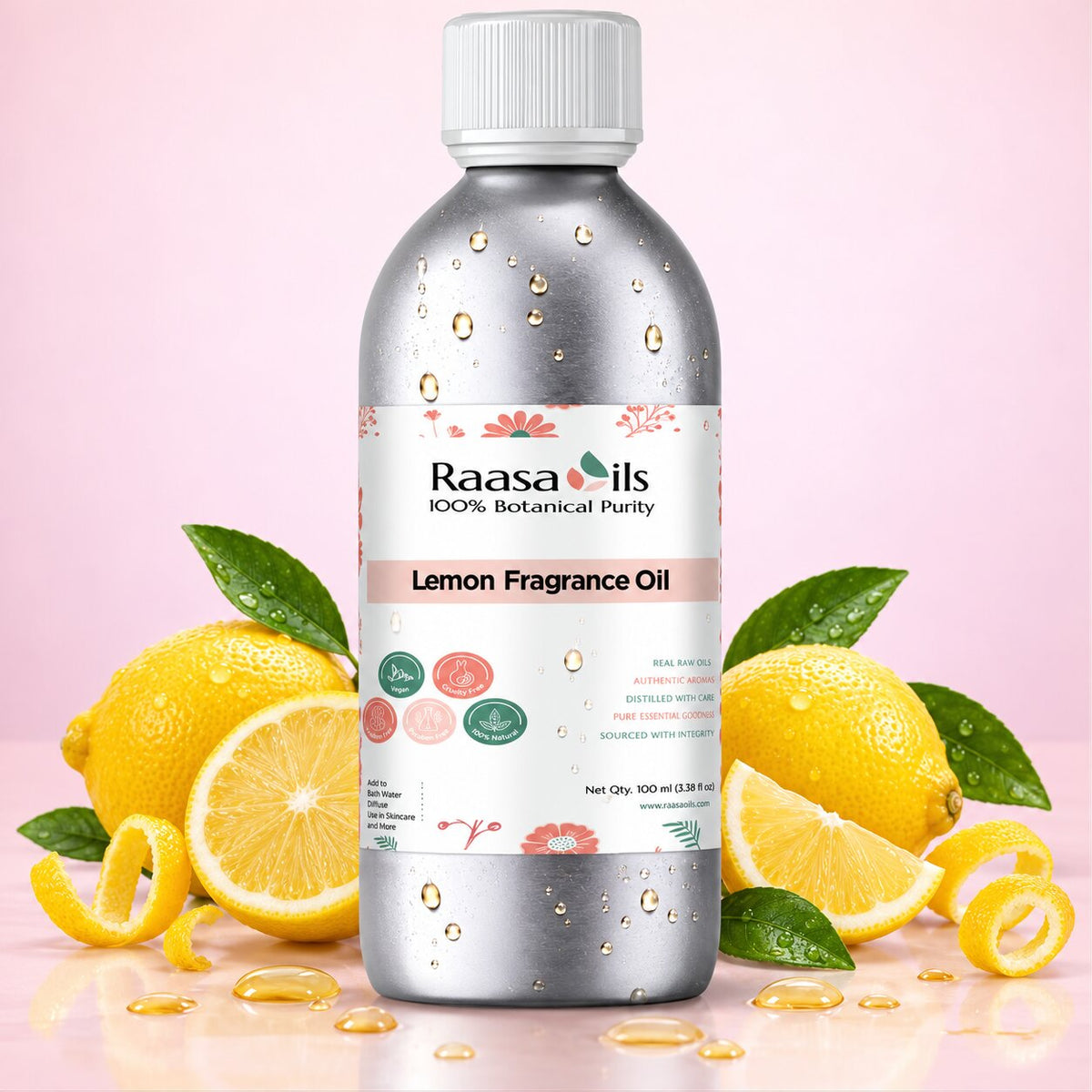A bottle of Raasa Oils Lemon Fragrance Oil centered on a soft pink background, surrounded by lemons, lemon slices, and green leaves with oil droplets around the bottle.