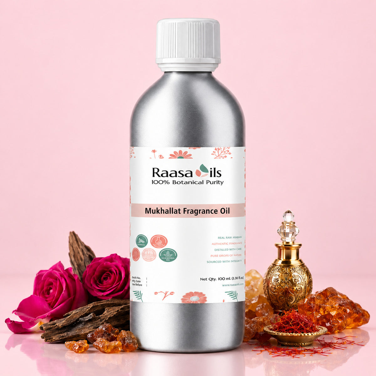 A bottle of Raasa Oils Mukhallat Fragrance Oil in a metallic silver bottle with a white cap, set against a soft pink background and styled with rose petals, amber crystals, and a decorative gold-toned perfume bottle.
