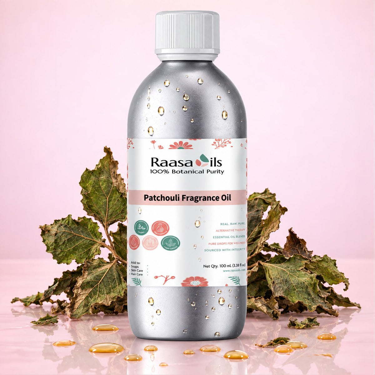 A bottle of Raasa Oils Patchouli Fragrance Oil, 100% botanical purity, in a metallic silver bottle with a white cap. The bottle is styled with fresh green patchouli leaves and scattered golden fragrance oil droplets on a reflective pink surface.