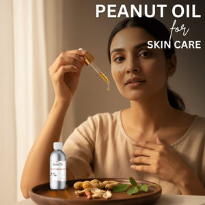 Woman applying peanut oil to her face with a dropper, surrounded by peanuts and a bottle of peanut oil.