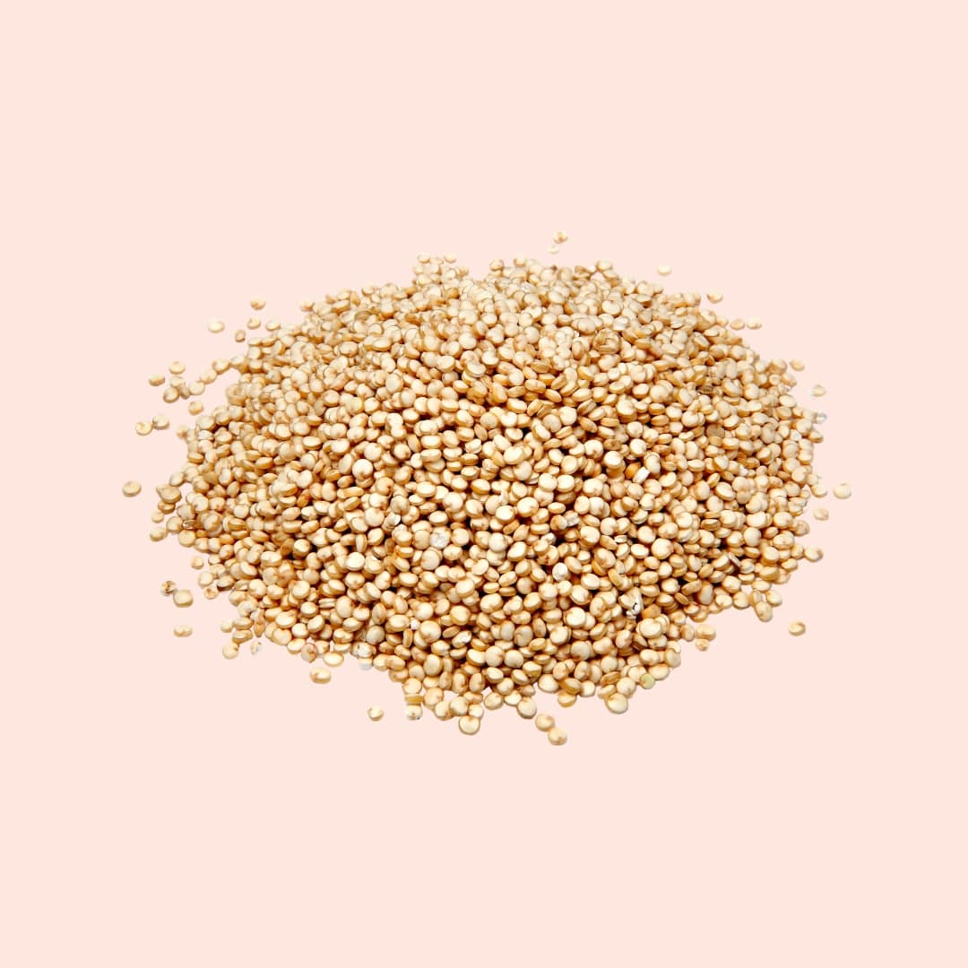Heap of quinoa seeds on a light pink background